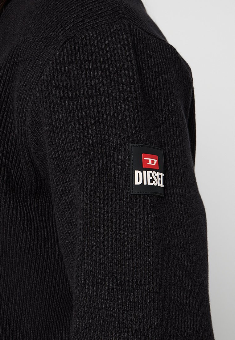 Maglione nero a coste con tessuto testurizzato, dotato di una patch con il logo Diesel rosso e bianco sulla manica sinistra.