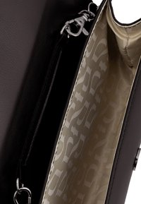 Borsa a tracolla nera in materiale sintetico con esterno liscio. L'interno presenta una fodera in tessuto crema con un motivo sottile e una tasca con zip.