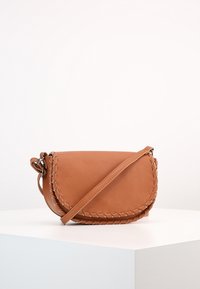 Borsa a tracolla in pelle marrone con patta curva, dettagli di cuciture decorative e tracolla regolabile. Texture liscia e design minimalista.