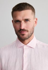 Roze linnen overhemd met een button-down kraag en witte knopen, met een gestructureerde stof en een iets relaxte pasvorm.