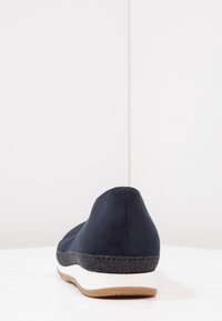 Námořnické modré slip-on boty s hladkou semišovou texturou, kontrastní černou podrážkou, zaoblenou špičkou a minimalistickým designem.