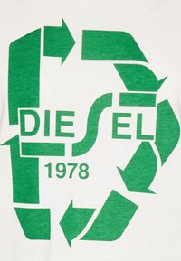 Biała koszulka T-shirt z zielonym logo recyklingu, z tekstem "DIESEL" i "1978" napisanym pogrubioną czcionką. Wykonana z bawełny o gładkiej strukturze.