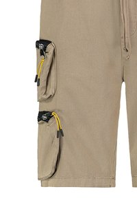 Beige Cargo-Shorts mit mehreren Reißverschluss-Taschen, schwarzem Besatz und gelben Kordelzügen, aus strapazierfähigem Material mit glatter Textur. 