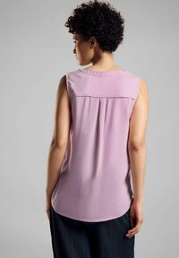Blusa senza maniche rosa con scollo rotondo, caratterizzata da una piega nella parte posteriore e una texture di tessuto morbido e leggero.