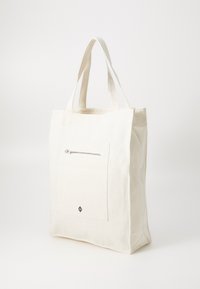 Cotton tote bag in off-white featuring two sturdy handles, a front zippered pocket, and a subtle logo at the bottom.