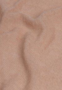 Tela de color rosa claro, de textura suave, con fibras visibles y pliegues suaves que crean un aspecto ondulado y acogedor. No hay personas ni objetos presentes.