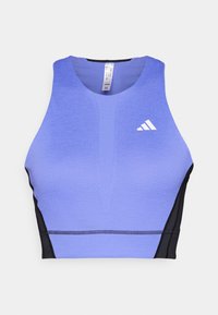 Lila Sport-Bh mit strukturiertem Oberflächen, schwarzen Seitenpanelen und einem weißen Logo auf der linken Brust. Sportliches Design mit rundem Ausschnitt.