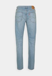 Jean en denim bleu clair à jambes droites vu de dos avec deux poches arrière et une pièce en cuir marron à la ceinture.