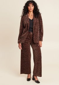 Leopardprint fluwelen blazer en wijde broek set in bruin en zwart. Kenmerkt zich door een losse pasvorm en textiele stof, gecombineerd met zwarte hakken.