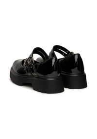 Zapatos de charol negro con dos hebillas ajustables, suela gruesa y texturizada, y diseño de punta redondeada. Incluyen correas en el tobillo y acabado brillante.