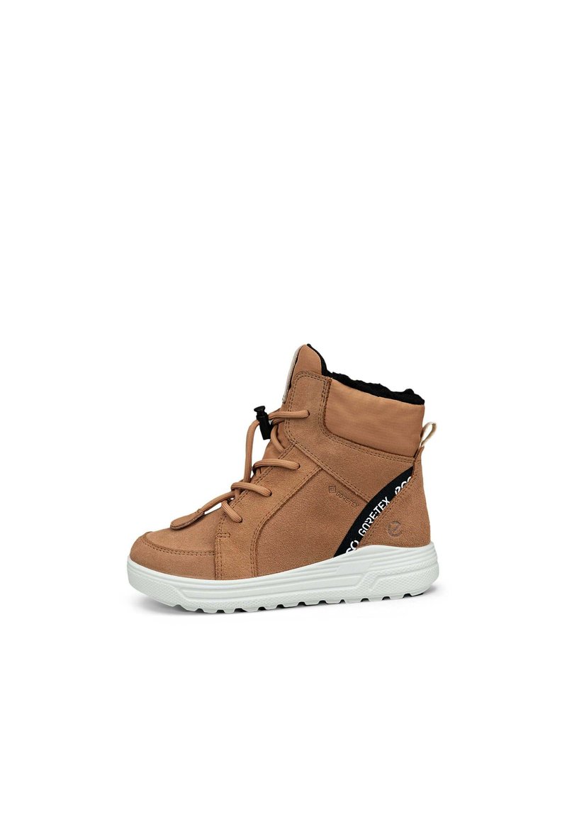 Stivaletto alla caviglia in suede beige con fodera in tessuto nero, suola bianca e cinturino di accento nero. Presenta un sistema di chiusura con lacci e un anello di estrazione sul retro.