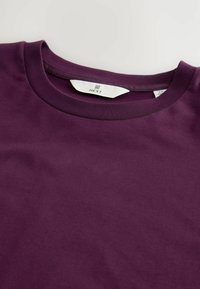 Paarse katoenen t-shirt met een ronde hals en een gladde textuur. Etiket zichtbaar in het halsgebied, waarop het merk "NEXT" en maat "M" staat.
