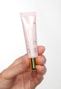 Rosa tub av Estée Lauder läppprodukt med gulddetaljer, som har en slät textur, smal form och vit märkning.