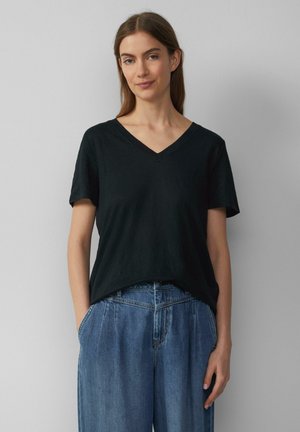T-shirt noir à manches courtes et col en V, fabriqué en tissu doux, associé à un jean en denim bleu clair à jambes larges. Design simple, sans motifs ni accents.