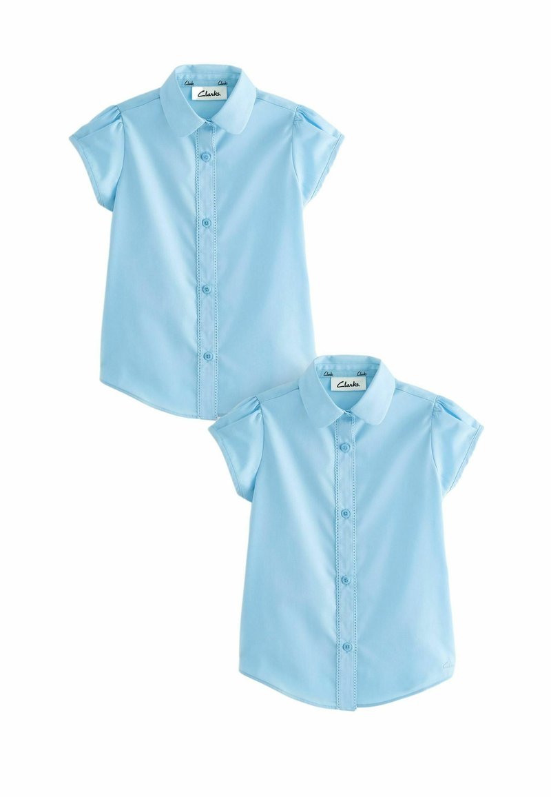 Camicia azzurro chiaro a maniche corte con colletto, caratterizzata da una chiusura con bottoni e dettagli sulle spalle arricciati. Due camicie esposte.
