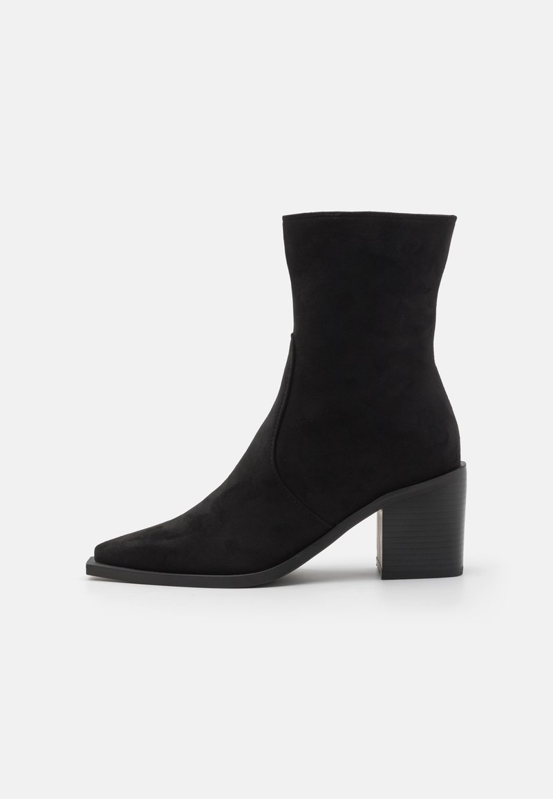 Botas de tobillo negras de ante con puntera puntiaguda, textura suave y un tacón chunky y texturizado para mayor estabilidad. Detalle de cierre con cremallera lateral.