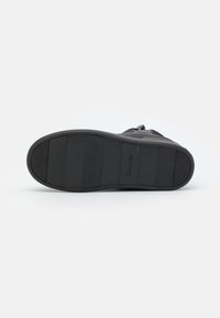 Černá sneaker podešev Calvin Klein; gumová podrážka se segmentovanou texturou, obsahující detail loga a plochý, mírně zakřivený design.