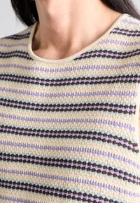 Dzianinowy top na ramiączkach z poziomymi paskami w kolorach kremowym, lawendowym, jasnoniebieskim i ciemnobrązowym. Okrągły dekolt o miękkiej fakturze.