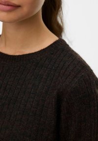 Donkere geribbelde trui met een ronde hals, met een zachte textuur en een aansluitende pasvorm, die het breipatroon in verschillende tinten bruin benadrukt.