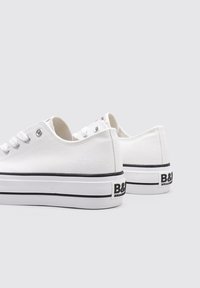 Baskets en toile blanches au design basse, semelle en caoutchouc noire et logo sur le talon. Comprend cinq œillets et des accents noirs contrastants.