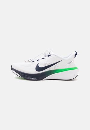 Weißer Nike-Laufschuh mit schwarzem Swoosh, schwarzen und grünen Sohlenakzenten und weißen Schnürsenkeln auf einfachem Hintergrund.