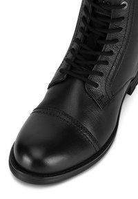 Czarne skórzane buty z gładką teksturą, zaokrąglonym noskiem i klasycznym sznurowanym zapięciem z sześcioma oczkami oraz dekoracyjnym przeszyciem.