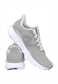 Zapatillas deportivas grises con parte superior de malla transpirable y suela de goma blanca. Incluyen cordones, logo sutil y detalles texturizados en el lateral.