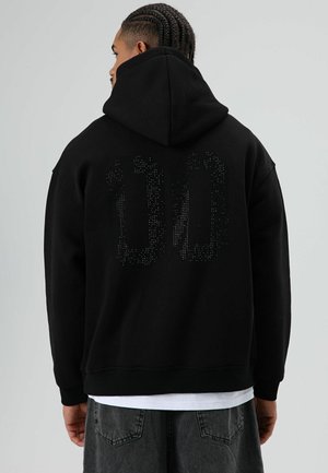 Zwarte hoodie met een grote "00" op de achterkant, versierd met strassteentjes. Voorzien van een capuchon met trekkoord en geribbelde boorden en zoom. Standaard pasvorm.