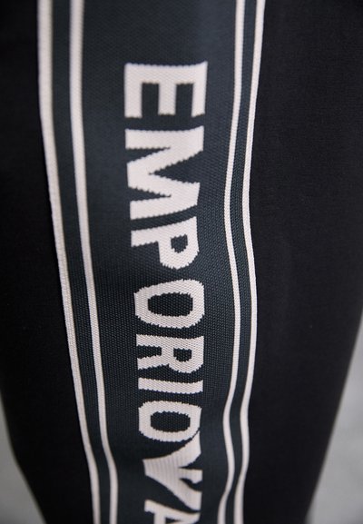 Must mustriga mustriga valge äärisega, millel on sõna "EMPORIO" julgete valgete tähtedega.