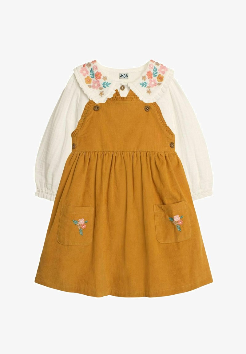 Braunes Corduroykleid mit bestickten Blumen-Taschen. Es hat eine weiße, langärmlige Bluse darunter und einen rüschierten Blumenkragen.