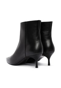 Botines de cuero negro con puntera afilada, textura suave y diseño de tacón kitten. Presentan una silueta simple y elegante.