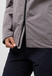 Lightweight gray jacket made of textured fabric, featuring a black zipper and contrasting dark trim at the hem and cuffs.