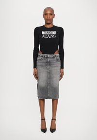 Top preto de manga longa com textura canelada e logótipo "MOSCHINO JEANS", combinado com uma saia lápis de denim cinza com fendas laterais e um corte justo.