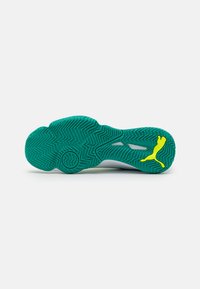 Semelle en caoutchouc verte avec un motif en zigzag, arborant un logo Puma jaune. Conçue pour l'adhérence et la performance lors d'activités sportives.