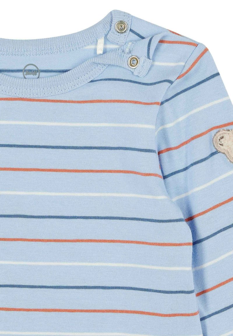 Helles blaues Langarmhemd mit horizontalen Streifen in Marineblau, Orange und Weiß. Verfügt über Druckknöpfe am Hals und ein Bären-Patch am Ärmel.