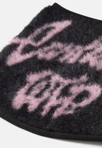 Tejido de mezcla de lana negra con una textura difusa que presenta un diseño de texto en cursiva rosa. Los bordes están recortados en negro. Forma redondeada.