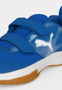 Μπλε αθλητικό παπούτσι Puma με λευκό λογότυπο, δύο ρυθμιζόμενους ιμάντες με βέλκρο, λευκή μεσαία σόλα και πορτοκαλί εξωτερική σόλα από καουτσούκ.