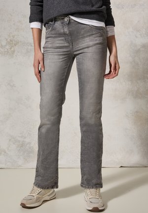Grijze denim spijkerbroeken met een relaxte pasvorm, subtiele vervaging en contraststiksels. Gecombineerd met lichtgekleurde sportschoenen.