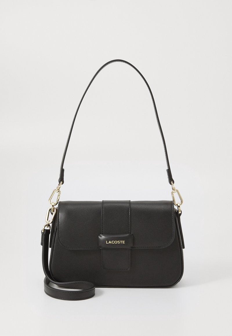Sac à bandoulière en cuir noir Lacoste avec fermeture à rabat, ferrures dorées et bandoulière réglable amovible sur fond uni.