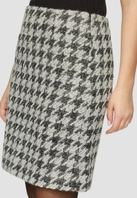 Falda de lana con estampado pata de gallo en blanco y negro, diseño ajustado con tejido texturizado y bolsillos en las costuras laterales, hasta la rodilla.