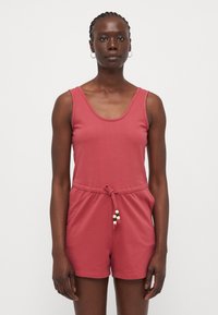 Combinaison rouge sans manches avec un col arrondi et une taille à cordon. Fabriquée en tissu doux, avec de petites perles sur le cordon.