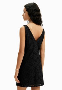 Čierne čipkované šaty s dizajnom V-vzadu, bez rukávov, krátka dĺžka a kvetinový vzor s textúrovaným povrchom.