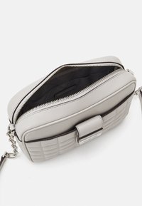 Borsa a tracolla in pelle grigia trapuntata con chiusura a zip, caratterizzata da accessori in argento e una tracolla piatta. L'interno presenta foderatura nera.