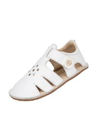 Sanda blanca de cuero con la punta cerrada y los laterales abiertos, equipada con una correa de Velcro y detalles perforados, sobre una suela de goma marrón.
