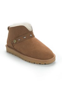 Botas de ante marrón hasta el tobillo con un cuello curvado, forro de felpa y tachuelas decorativas plateadas a lo largo de la correa. Suela de goma plana con agarre texturizado.