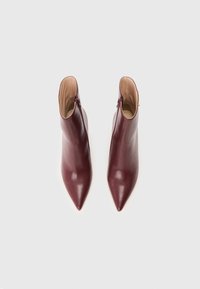 Bottes de cheville en cuir bordeaux à bout pointu ; texture lisse et fermeture éclair sur le côté ; design structuré avec une silhouette élancée.