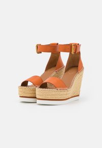 Sandali wedge in pelle arancione con cinturino alla caviglia, dettagli in juta sul wedge e suola in gomma bianca. Design con punta aperta.