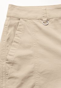 Béžové kalhoty z bavlněné směsi s vysokým pasem, sklady na přední straně a stříbrným kovovým detailem na pase.