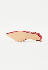Rød lakkert skinnpumps med spiss tå, lav blokkhelt og slingback-design. Har teksturert krokodillemønster og lys såle.