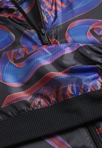 Černá bunda na zip s abstraktním vícetrubkovým vzorem v modré a červené barvě, s texturovaným černým síťovaným lemem a mřížkovaným potiskem.